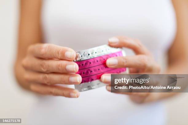 woman's hand holding birth control pills, cropped - verhütungsmittel stock-fotos und bilder