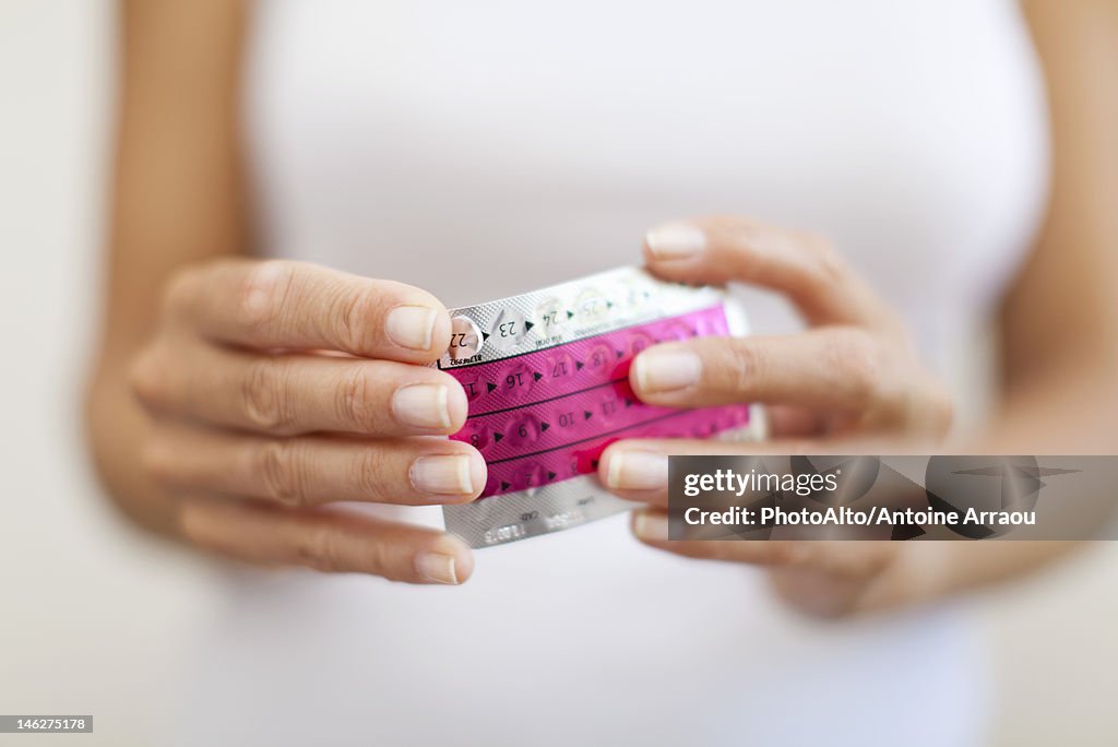 Woman's hand holding birth control pills, cropped