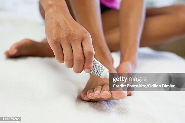 woman applying ointment to foot, low section - female feet stockfoto's en -beelden