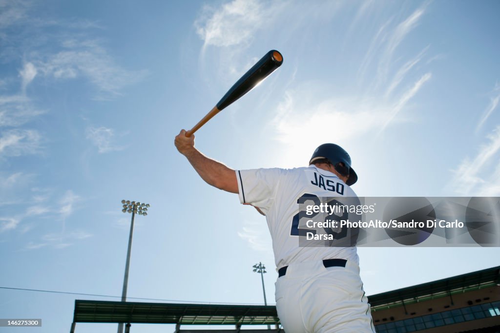 Baseball player swinging bat, rear view