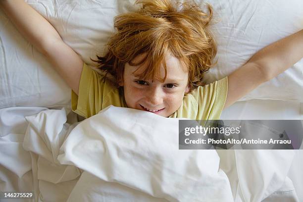 boy lying in bed with arms outstretched - wake up happy stock pictures, royalty-free photos & images