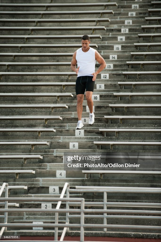 Male athlete running down stadium steps