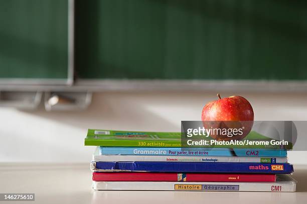 apple on top of stacked books - textbook stack stock pictures, royalty-free photos & images