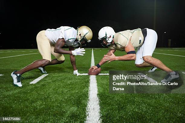 opposing football players crouched at line of scrimmage - football line of scrimmage stock pictures, royalty-free photos & images