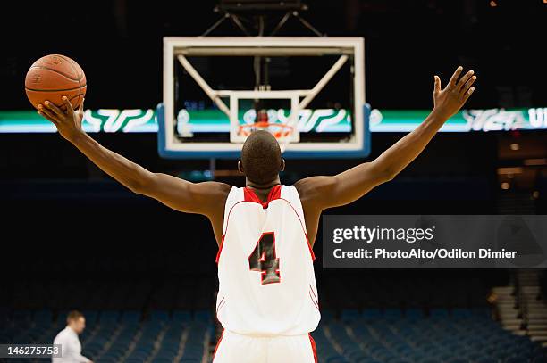 basketball player standing in basketball court with arms outstretched, rear view - basketball jersey stock pictures, royalty-free photos & images