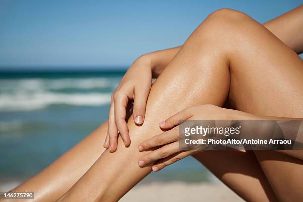 woman rubbing legs, low section - bräune stock-fotos und bilder