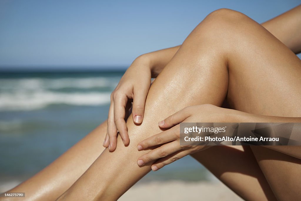 Woman rubbing legs, low section