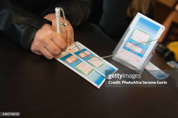 hands of woman filling out lottery tockets - loto photos et images de collection