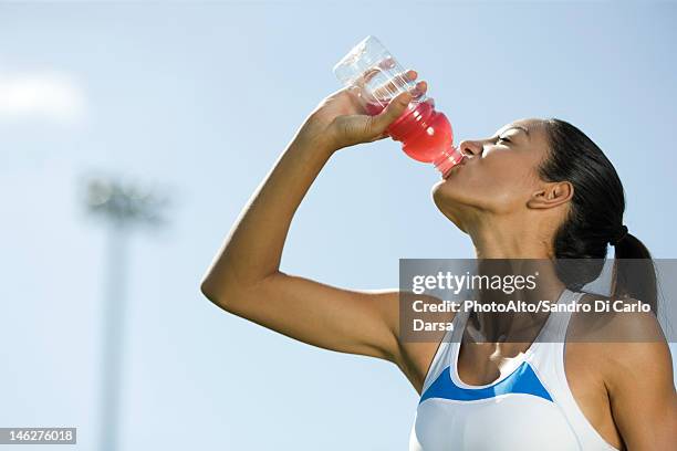 young female athlete drinking sports drink, portrait - energydrink stock-fotos und bilder