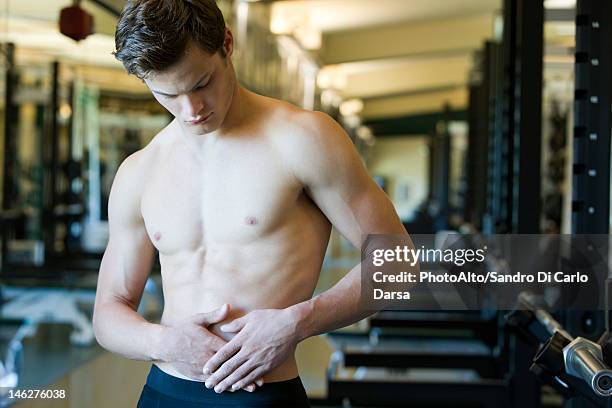 barechested man with hands on stomach - men stomach pain stock-fotos und bilder