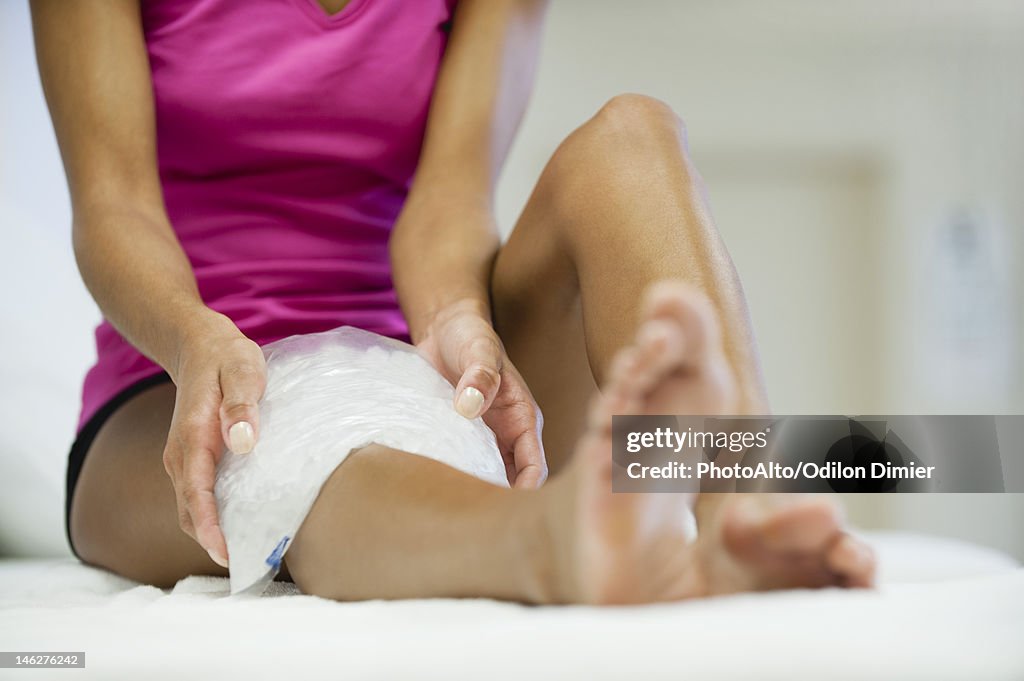 Woman sitting with ice pack on knee