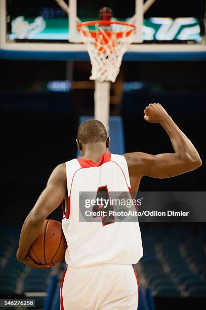 basketball with fist raised in victory, rear view - basketbaltenue stockfoto's en -beelden