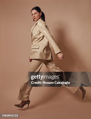 Masculine-looking beautiful woman in a leather suit is jumping in front of a brown background. Masculine-looking beautiful woman in a leather suit is jumping in front of a brown background.