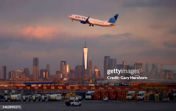 United Airlines airplane takes off from Newark Liberty Airport at sunset in front of lower Manhattan and One World Trade Center in New York City on...