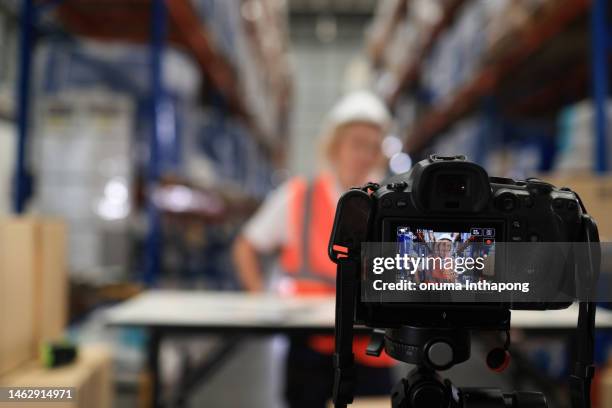 cámara profesional sin espejo disparando personal de inventario femenino con chaleco de seguridad trabajando duro en almacén, gestión de inventario - servizio fotografico fotografías e imágenes de stock