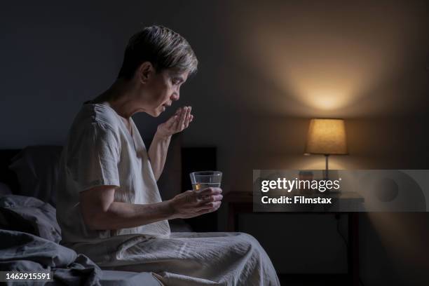 寝室で薬を飲んでいる女性 - bedroom photos ストックフォトと画像