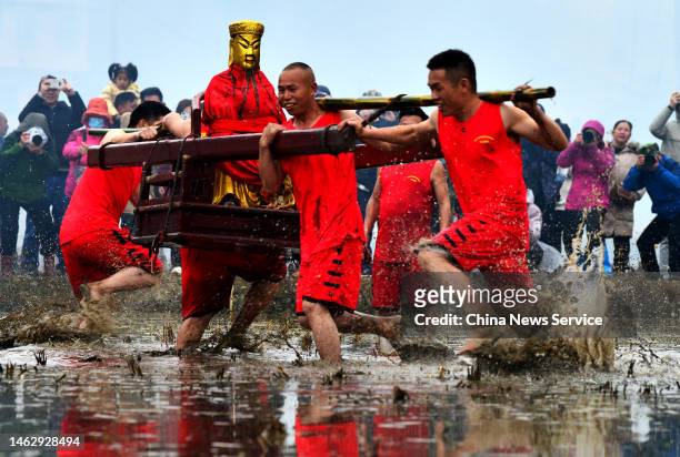 Villagers carrying a statue of Guan Gong run in a muddy field during a traditional Hakka ceremony to welcome the arrival of spring on February 4,...