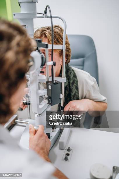 doctor ophthalmologist examining patient's eyes stock photo - eye test equipment stock pictures, royalty-free photos & images