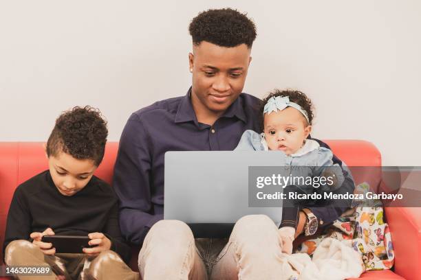 ecuadorian father accompanied by his son and daughter on the sofa in his living room - famiglia multimediale foto e immagini stock