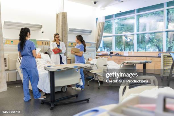 chirurgin steht mit den beiden medizinstudenten im lernlabor des krankenhauses - medizinische fakultät stock-fotos und bilder
