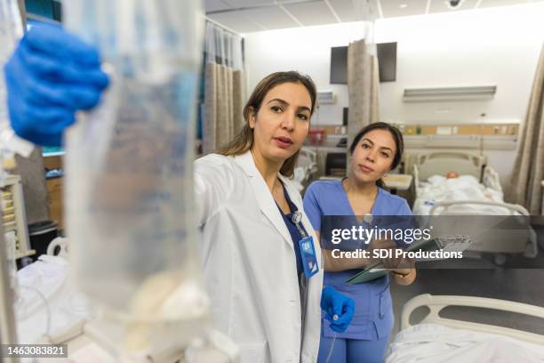 hospital instructor and medical student examine iv bag - bedside manner stock pictures, royalty-free photos & images