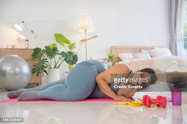 plus size woman sleeping on exercise mat and does not want to exercise. - self development stock pictures, royalty-free photos & images