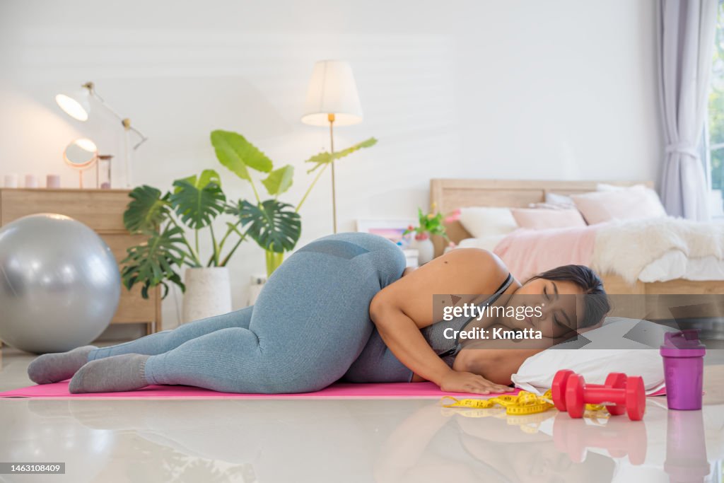 Plus size woman sleeping on exercise mat and does not want to exercise.