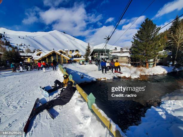 skiers loading on the challenger lift and passing over the river at the warm springs area,  sun valley ski resort, idaho. - ketchum idaho stock pictures, royalty-free photos & images