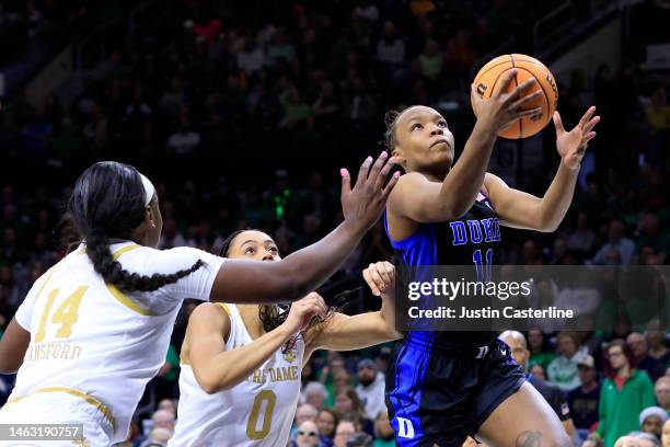 Jordyn Oliver of the Duke Blue Devils drives to the basket while defended by KK Bransford and Jenna Brown of the Notre Dame Fighting Irish during the...