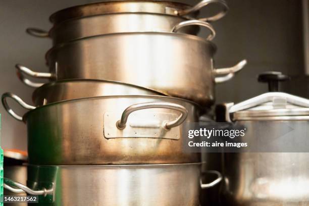 close-up of a pile of steel pots and pans stacked in a restaurant kitchen in a row, front view - cooking pan stock pictures, royalty-free photos & images