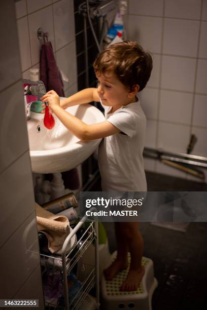 boy playing  on sink alone in house - lava lamp fotografías e imágenes de stock