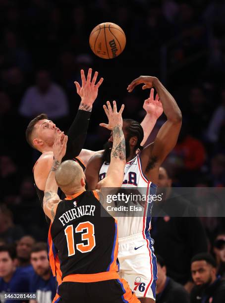 James Harden of the Philadelphia 76ers passes under pressure from Evan Fournier and Isaiah Hartenstein of the New York Knicks in the fourth quarter...