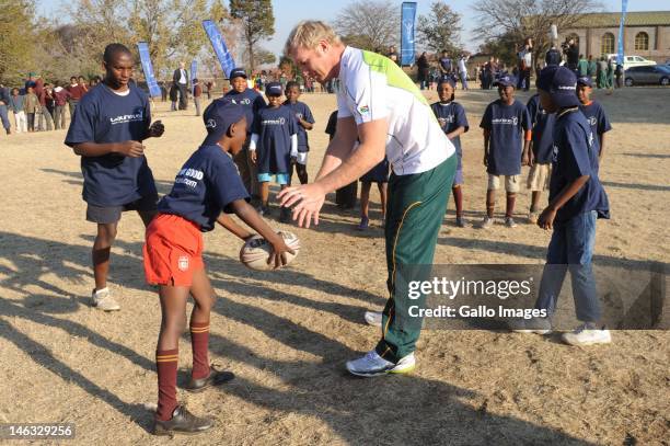 Schalk Burger helps Xolalni Vilakazi during the Laureus Soweto Schools Rugby Project visit at Tswelelang Primary School on June 14, 2012 in Soweto,...