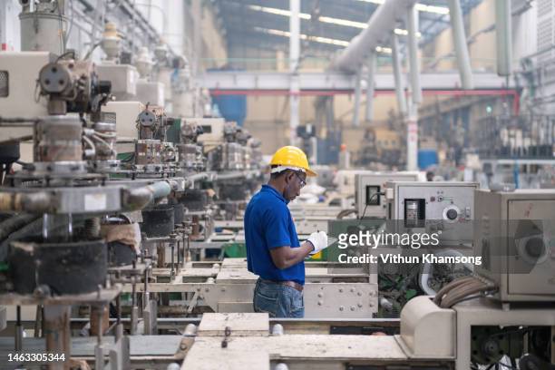 Male manufacturers african working on production line at plastic bag machine