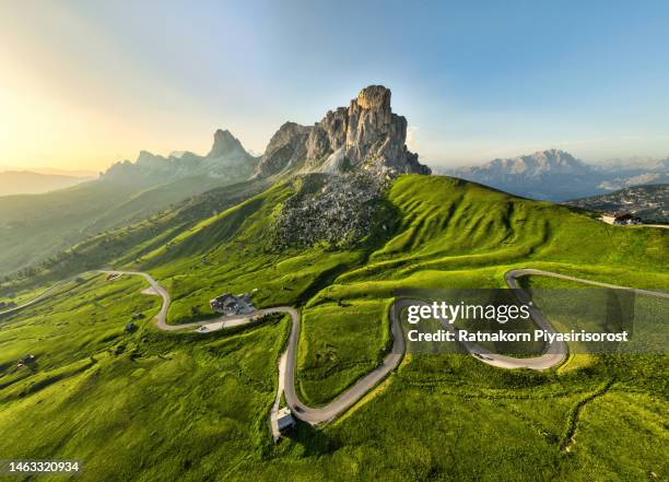 aerial view of a road winding through a dense green forest in dolomites national park, drone panoramic photo of the beautiful mountain pass hidden in the autumnn pine forest with the soft light of the autumn sunset, dolomites alps, south tyrol, italy - high street fotografías e imágenes de stock