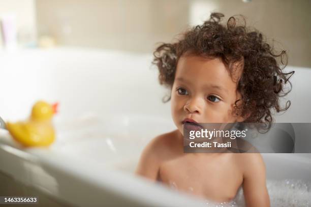 bubble bath, girl and rubber duck in water, soap and foam for body care, cleaning and fun. kids, shower toys and washing in bathtub, bathroom and fresh skincare for healthy life, wellness and children - bath girl stockfoto's en -beelden