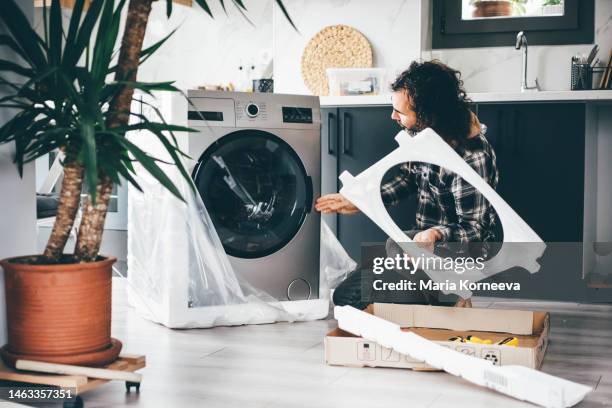 man unpacking washing machine. new washing machine. moving in a new home. - buying washing machine stock pictures, royalty-free photos & images