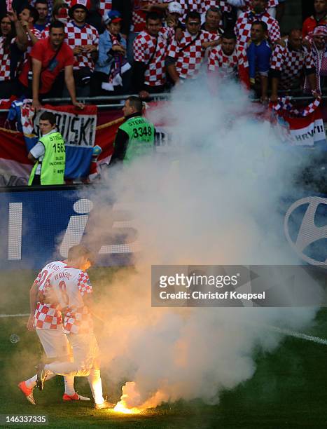 Ognjen Vukojevic and Ivan Perisic of Croatia look at flare that has been thrown onto the pitch during the UEFA EURO 2012 group C match between Italy...