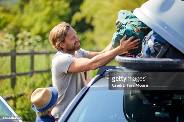 father and son loading luggage  into car - holiday packing stockfoto's en -beelden