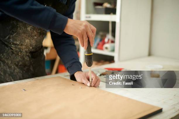 screwdriver, wood frame and construction man hands doing home renovation project. art frames, handyman and interior design job of a professional builder with a nail doing house development for work - handyman stockfoto's en -beelden