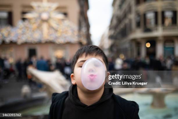 young boy blowing large bubble with gum on the street in a big city. - bubble gum stockfoto's en -beelden