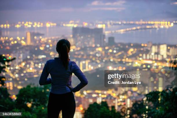 woman hiker looking at the cityscape view from the hill - terrasse panoramique photos et images de collection