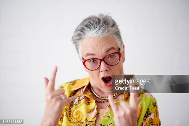 rock hand sign, senior woman and portrait of a metal, punk and crazy female in a studio. isolated, white background and emoji hand of a excited elderly face feeling cool and ready for a celebration - excitement emoji stock pictures, royalty-free photos & images