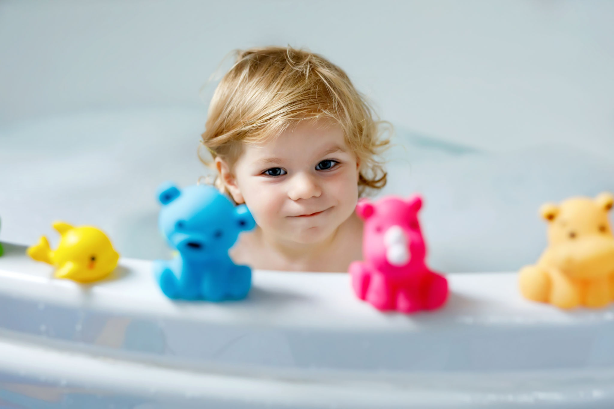 Adorable cute little toddler girl taking bath in bathtub. Happy healthy baby child playing with rubber gum toys and having fun. Washing, cleaning, hygiene for children. Adorable cute little toddler girl taking bath in bathtub. Happy healthy baby child playing with rubber gum toys and having fun. Washing, cleaning, hygiene for children.
