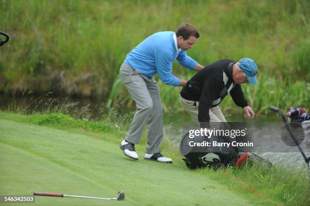 Michael Dixon of the K Club helps his teammate Tony Hayes fish his trolley and clubs out of a pond after it fell in during the Virgin Atlantic PGA...