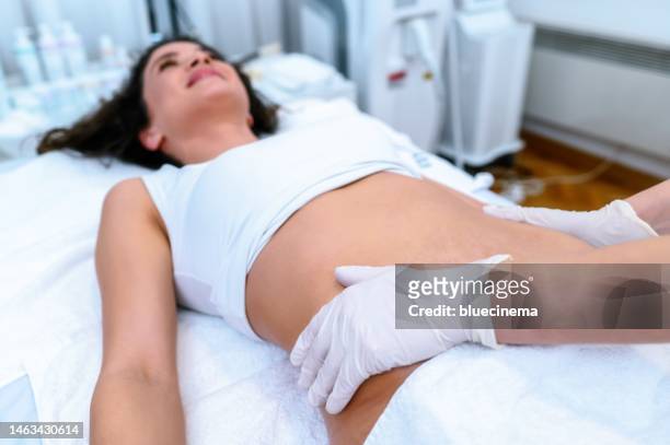 kosmetikerin wendet die creme frau auf den magen mit dehnungsstreifen - liposuction stock-fotos und bilder