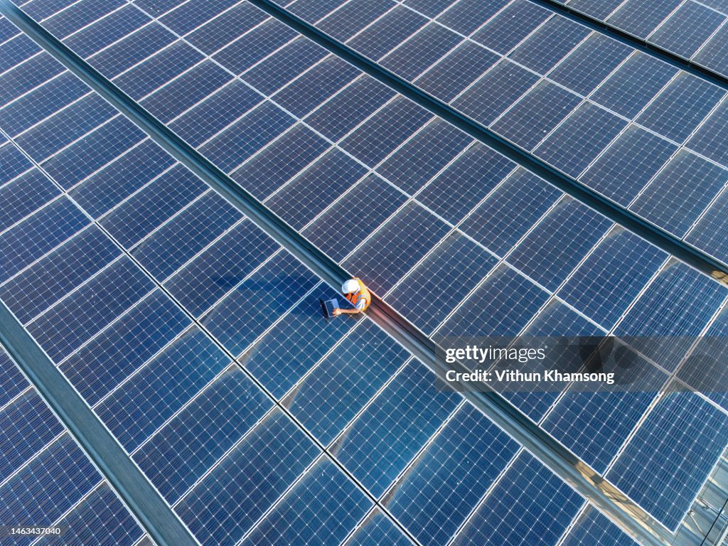 Aerial view of Engineers and laptop at solar panels roof