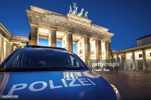 police car in front of the brandenburg gate (berlin, germany) - car alarm stock-fotos und bilder