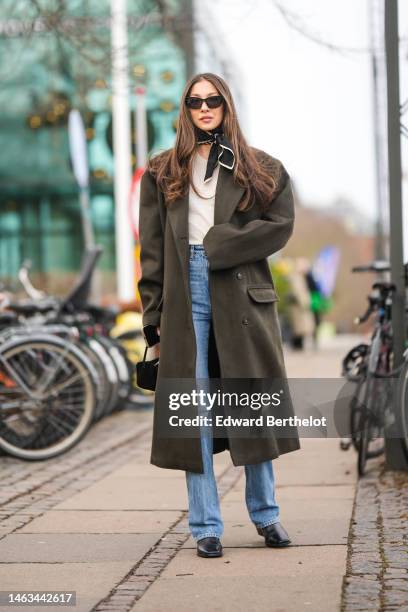 Guest wears black sunglasses, a white V-neck t-shirt, a khaki brown oversized long coat, a black with white print pattern silk scarf, a black velvet...