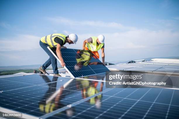 dois trabalhadores instalando sistema fotovoltaico. - energia solar - fotografias e filmes do acervo